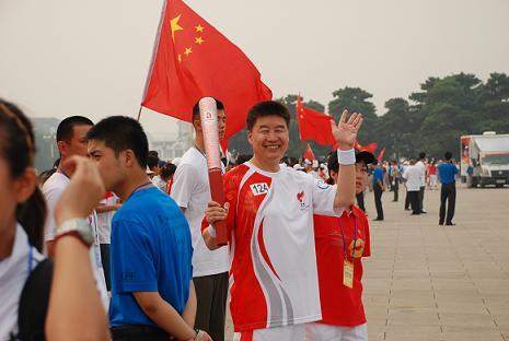 Mr. Peng XiaoHai, GM of Beijing Hualian Hypermarket, is doing the torch relay in front of Tian   an Men.